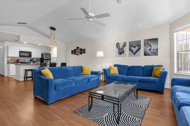 living room featuring ceiling fan, lofted ceiling, and wood-type flooring