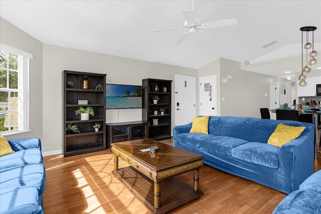 living room featuring vaulted ceiling, light hardwood / wood-style floors, and ceiling fan