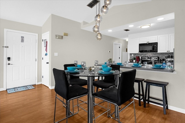 dining area featuring lofted ceiling and hardwood / wood-style flooring