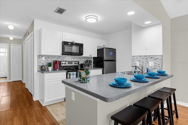 kitchen featuring sink, a breakfast bar area, appliances with stainless steel finishes, white cabinetry, and kitchen peninsula