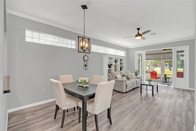 dining area with crown molding, ceiling fan with notable chandelier, and light hardwood / wood-style floors