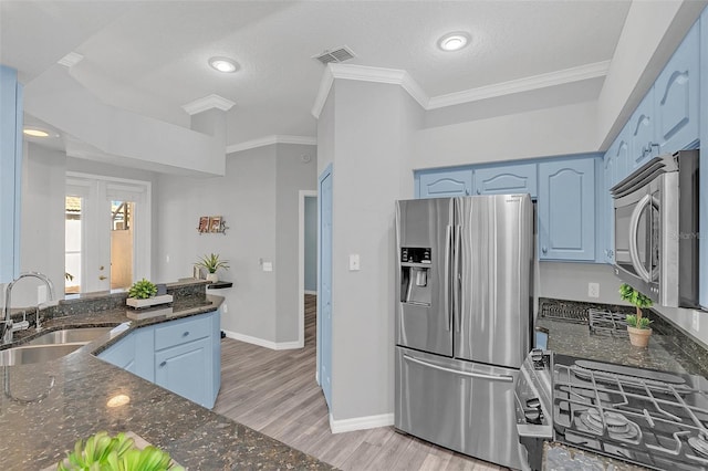 kitchen featuring sink, dark stone countertops, stainless steel appliances, blue cabinetry, and light wood-type flooring