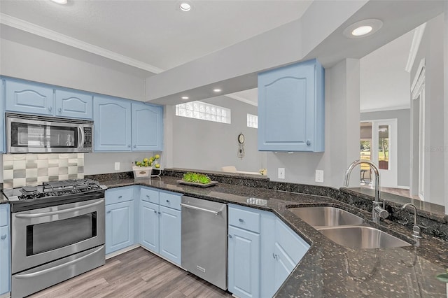 kitchen with blue cabinets, sink, crown molding, appliances with stainless steel finishes, and dark stone counters