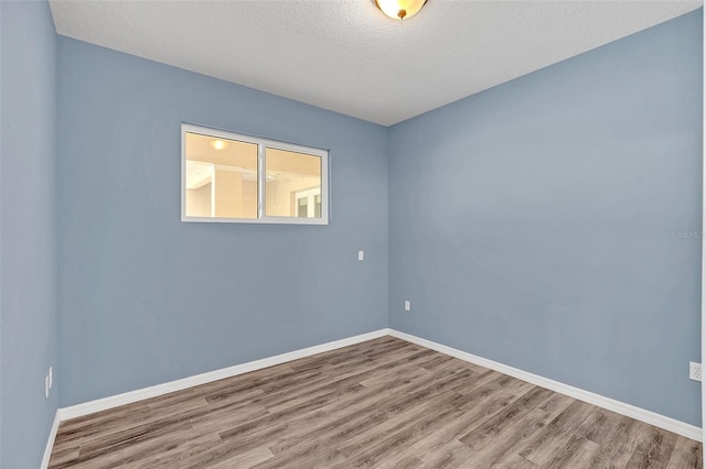 unfurnished room with wood-type flooring and a textured ceiling