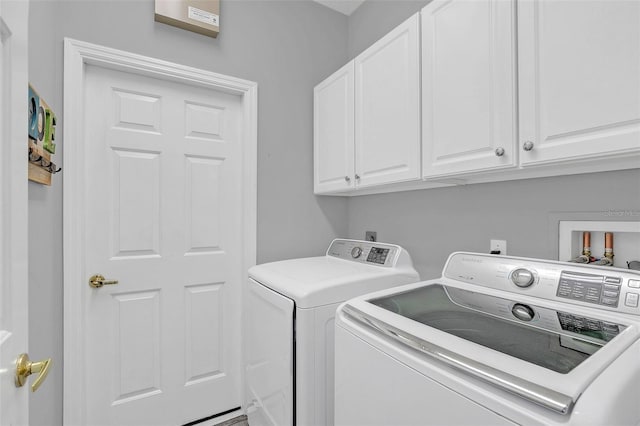 clothes washing area featuring cabinets and washer and clothes dryer