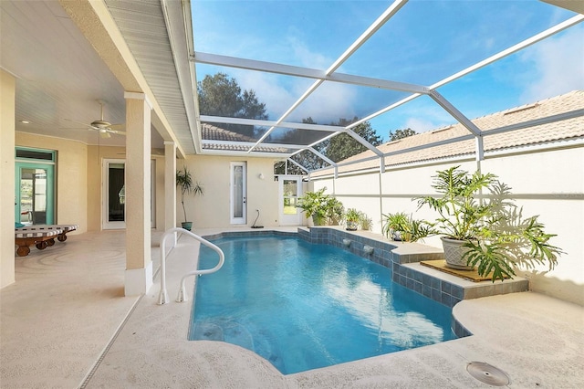 view of swimming pool featuring pool water feature, a patio, ceiling fan, and glass enclosure