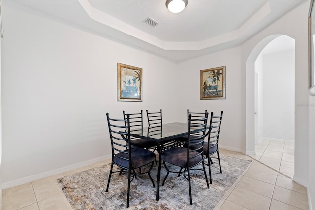 dining room featuring a raised ceiling and light tile patterned floors