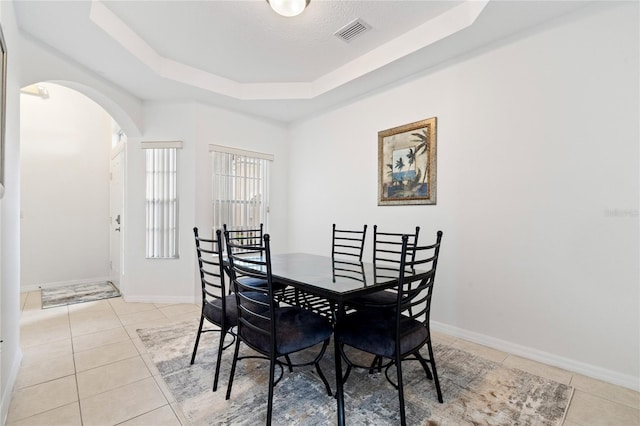 dining room featuring a raised ceiling and light tile patterned flooring