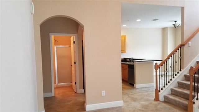 corridor with arched walkways, light tile patterned flooring, recessed lighting, baseboards, and stairway