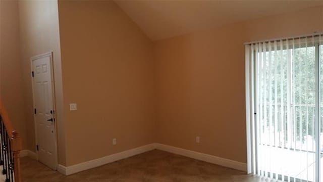 carpeted spare room with lofted ceiling and baseboards