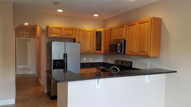 kitchen with arched walkways, recessed lighting, stainless steel appliances, a peninsula, and a kitchen bar