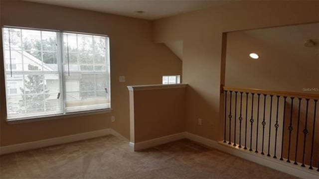 spare room with carpet floors, a wealth of natural light, and baseboards