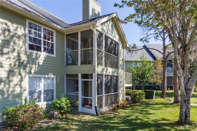 view of home's exterior featuring a sunroom, a chimney, and a yard