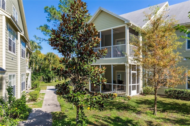 view of side of home with a sunroom and a lawn