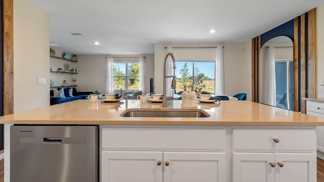 kitchen with dishwasher, a kitchen island with sink, sink, and white cabinets