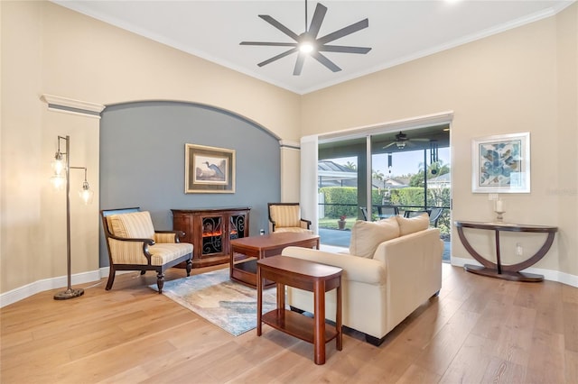 living room with ornamental molding, ceiling fan, and light wood-type flooring