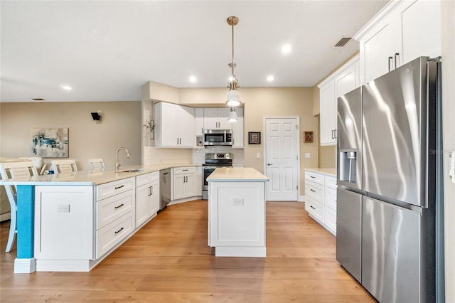 kitchen featuring a breakfast bar, white cabinetry, decorative light fixtures, kitchen peninsula, and stainless steel appliances