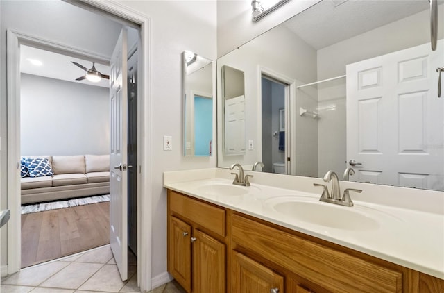 bathroom featuring ceiling fan, tile patterned flooring, vanity, toilet, and walk in shower