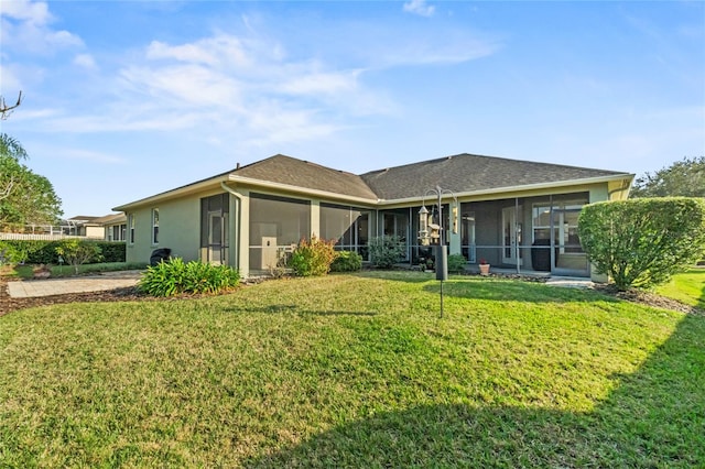 rear view of house featuring a yard and a sunroom