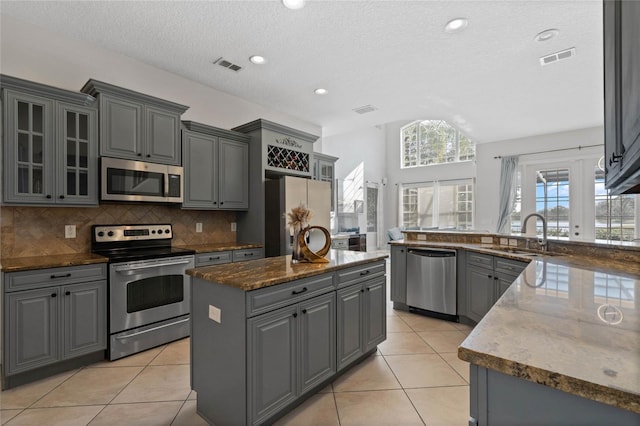 kitchen featuring light tile patterned flooring, sink, gray cabinetry, appliances with stainless steel finishes, and a kitchen island