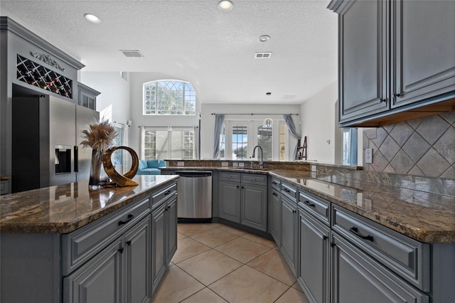 kitchen featuring gray cabinets, appliances with stainless steel finishes, tasteful backsplash, sink, and kitchen peninsula