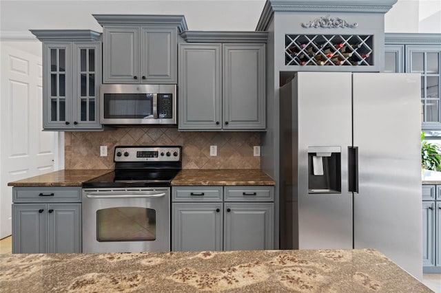 kitchen featuring appliances with stainless steel finishes, decorative backsplash, and dark stone counters