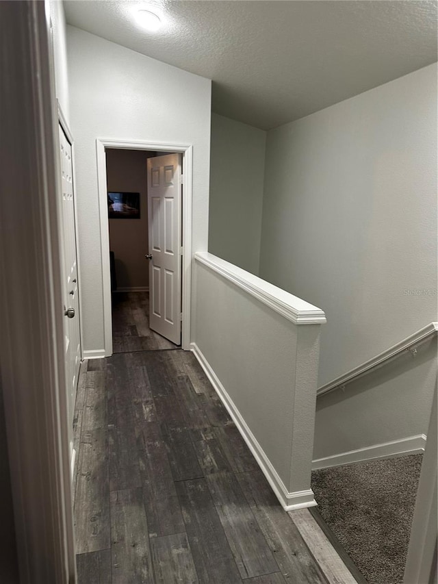 corridor featuring a textured ceiling and dark hardwood / wood-style flooring