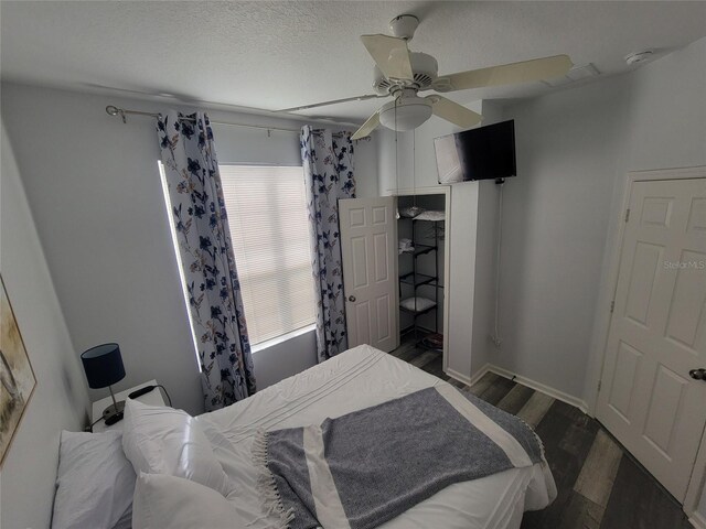 bedroom with ceiling fan, dark hardwood / wood-style floors, and a textured ceiling