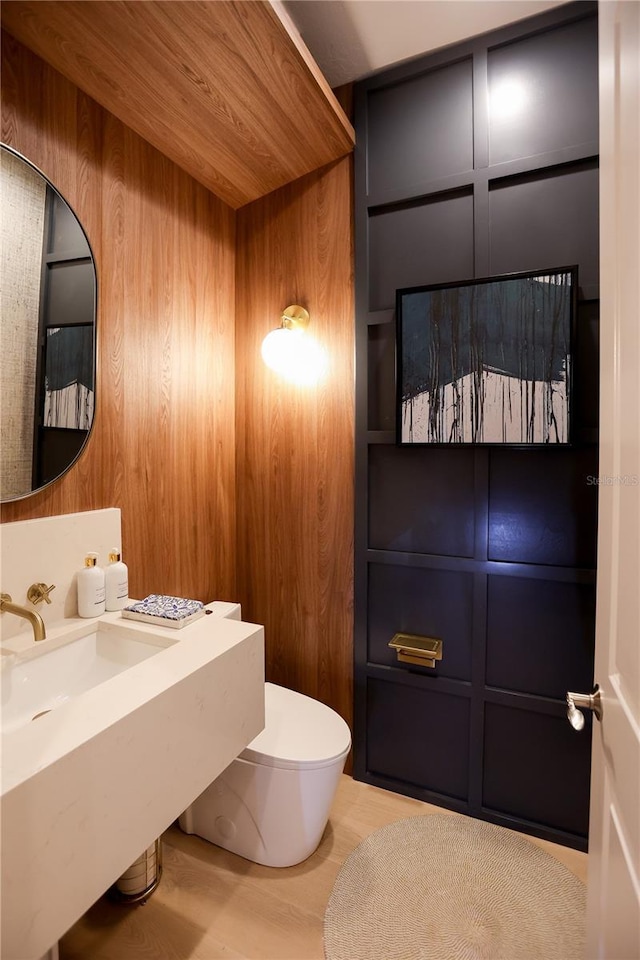 bathroom featuring wooden walls and toilet