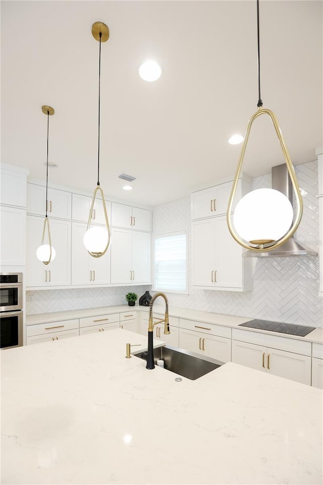 kitchen with black electric cooktop, sink, and decorative light fixtures