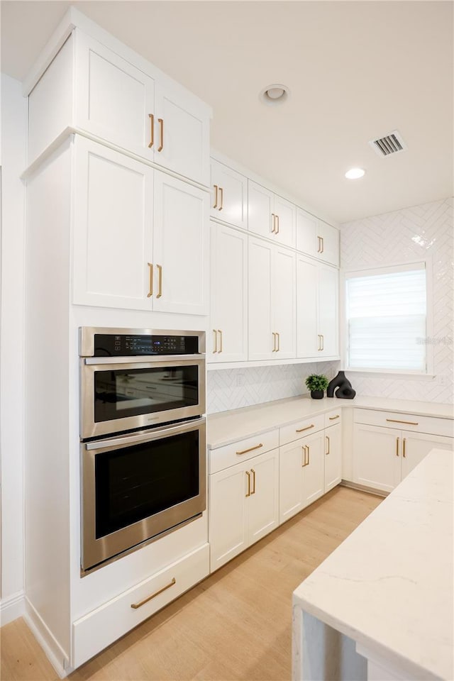 kitchen featuring white cabinetry, light wood-type flooring, and double oven