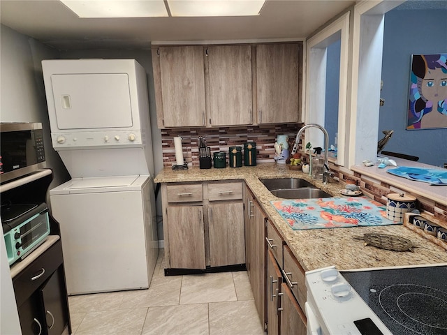 kitchen with stacked washer and dryer, sink, light tile patterned floors, electric stove, and backsplash