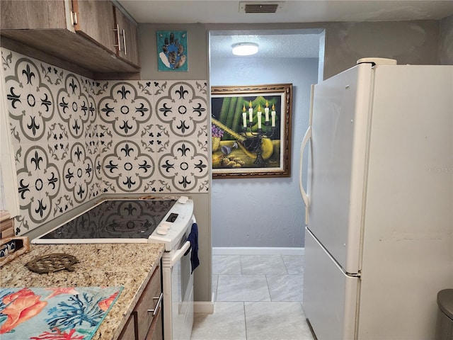 kitchen with light stone counters, white appliances, and light tile patterned floors