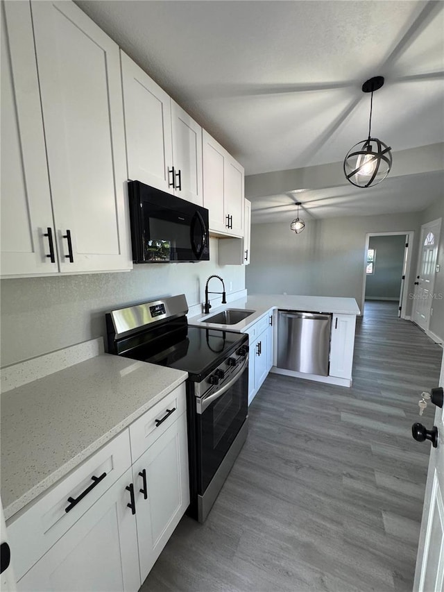 kitchen with appliances with stainless steel finishes, sink, white cabinets, and decorative light fixtures