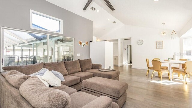 living room featuring light hardwood / wood-style flooring, high vaulted ceiling, and a healthy amount of sunlight