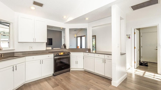 kitchen with electric stove, light hardwood / wood-style floors, kitchen peninsula, and white cabinets