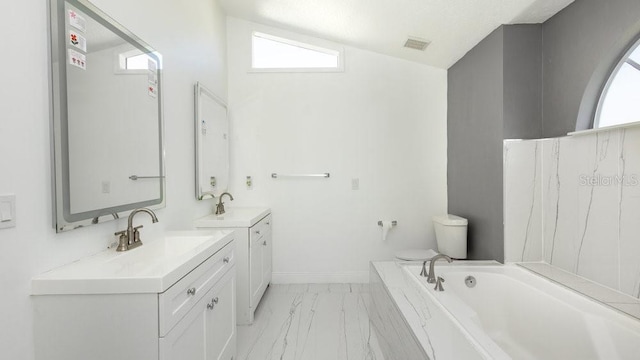 bathroom with vanity, a healthy amount of sunlight, a bathtub, and toilet