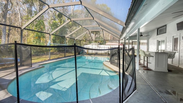 view of swimming pool with exterior bar, a patio area, and a lanai