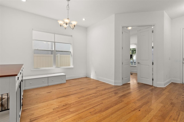 unfurnished dining area with light hardwood / wood-style floors and a chandelier