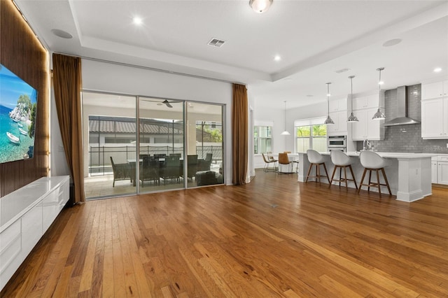 unfurnished living room featuring hardwood / wood-style floors, a tray ceiling, and sink