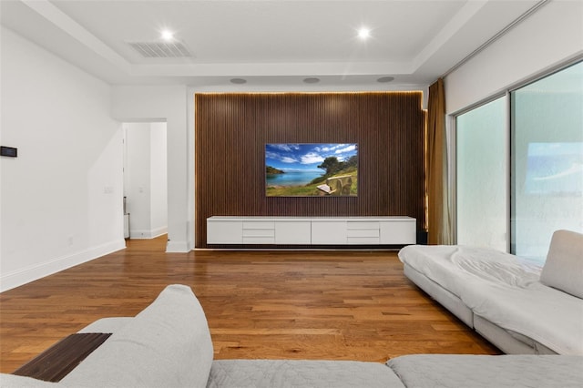 home theater room with hardwood / wood-style floors and a tray ceiling