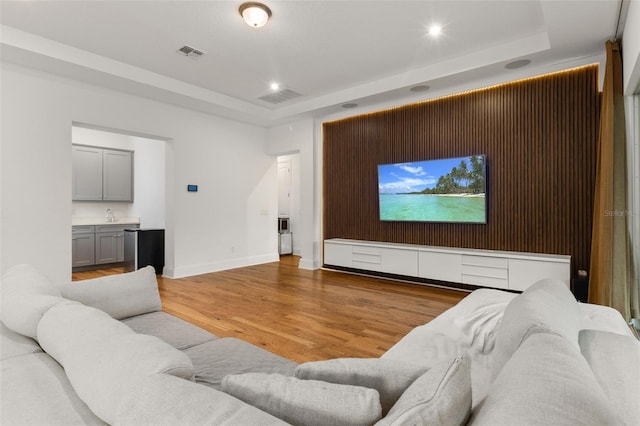 home theater with a tray ceiling and hardwood / wood-style flooring