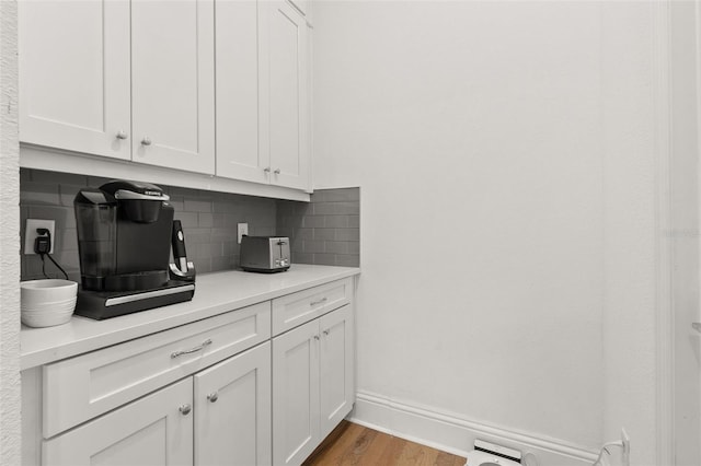 kitchen with white cabinetry, decorative backsplash, and light hardwood / wood-style flooring