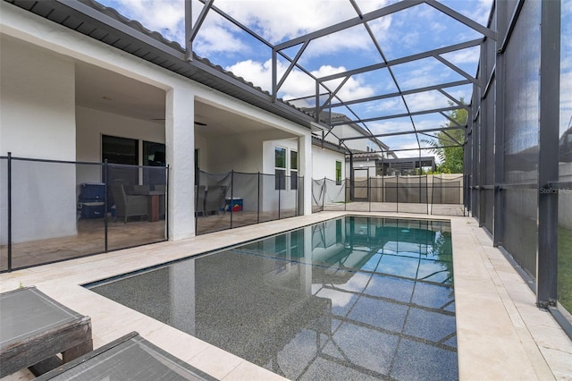 view of swimming pool with a patio, ceiling fan, and glass enclosure