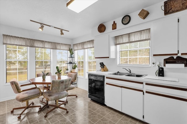 kitchen with black dishwasher, sink, white cabinets, and track lighting