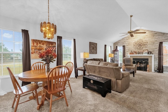 carpeted dining space with ceiling fan with notable chandelier, vaulted ceiling, and a tile fireplace