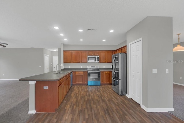 kitchen featuring sink, hanging light fixtures, kitchen peninsula, stainless steel appliances, and dark wood-type flooring