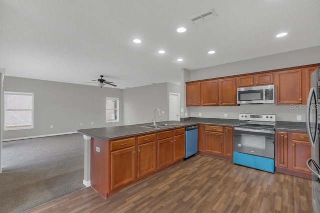 kitchen featuring sink, dark hardwood / wood-style flooring, ceiling fan, kitchen peninsula, and stainless steel appliances