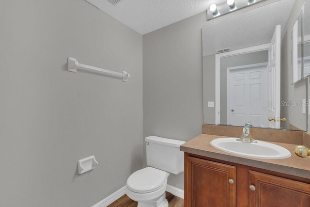 bathroom featuring vanity, wood-type flooring, a textured ceiling, and toilet