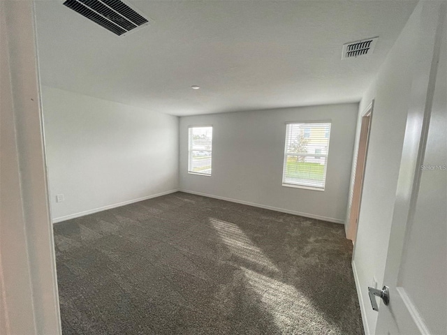 unfurnished room with dark carpet